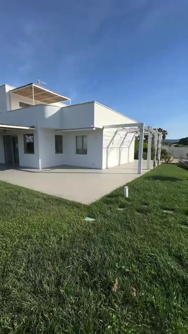Villa bianca con prato curato e pergolato