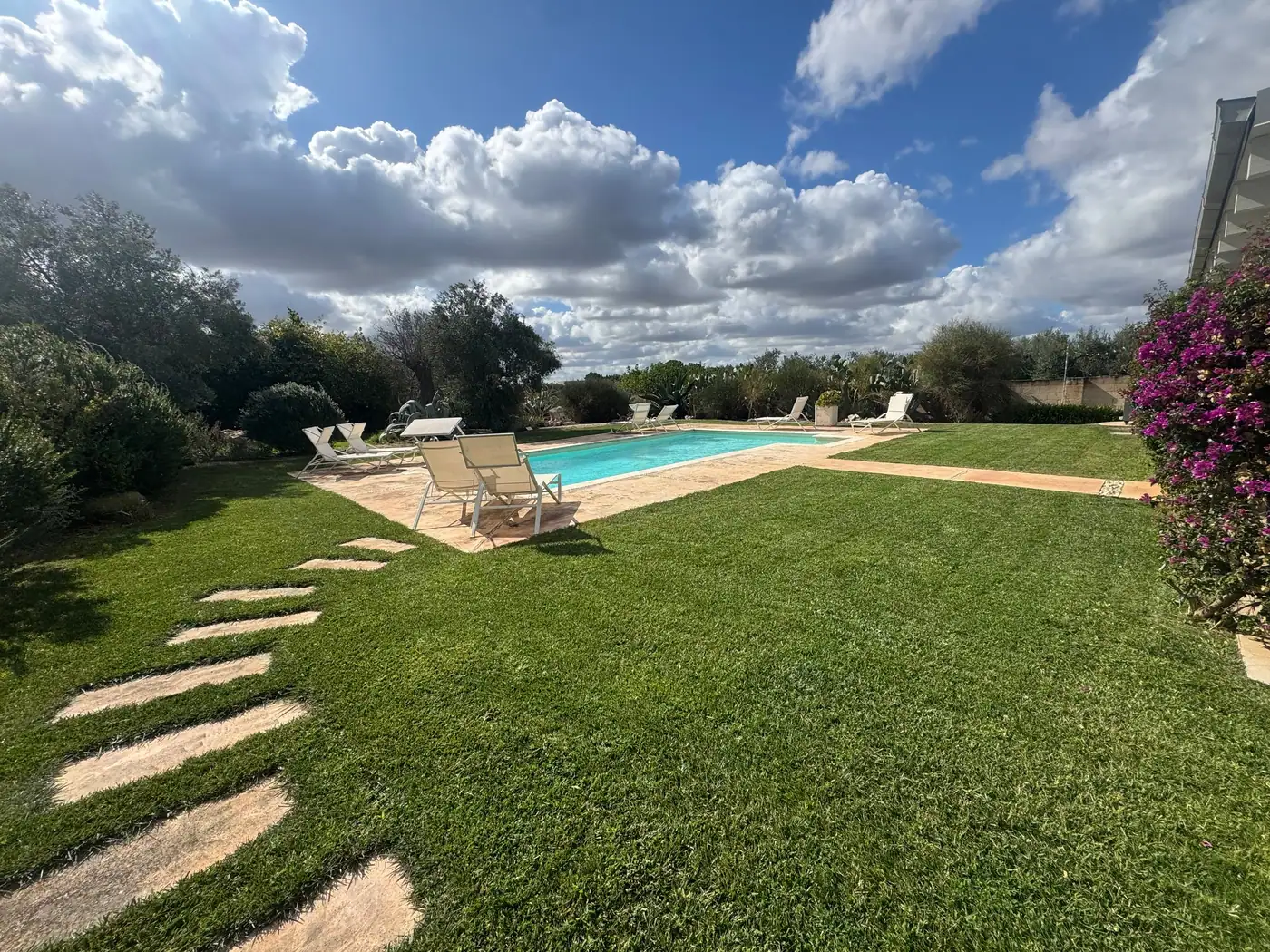 Prato all’inglese con camminamento in pietra attorno alla piscina di una villa curata da Cesarino Giardini