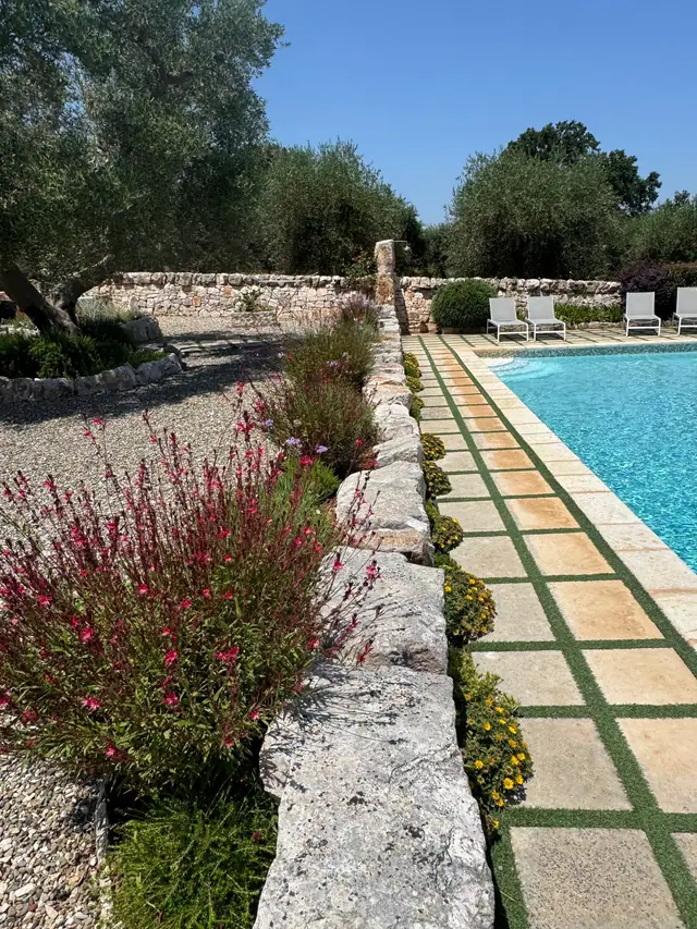 Aiuole fiorite e muretto a secco lungo il bordo della piscina