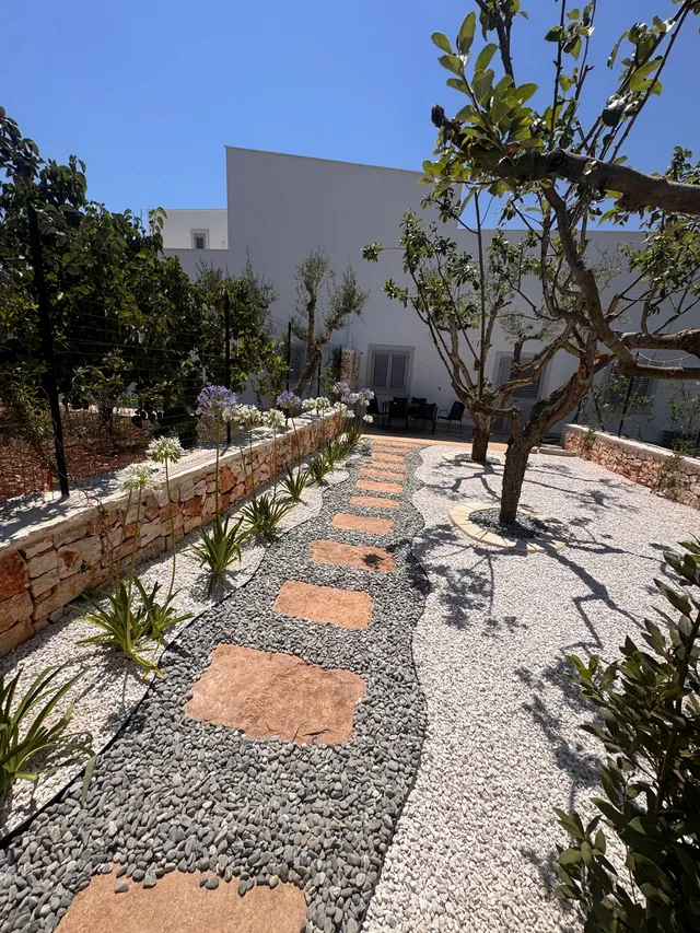 Gravel path between citrus trees and flower beds in a garden landscaped by Cesarino Giardini