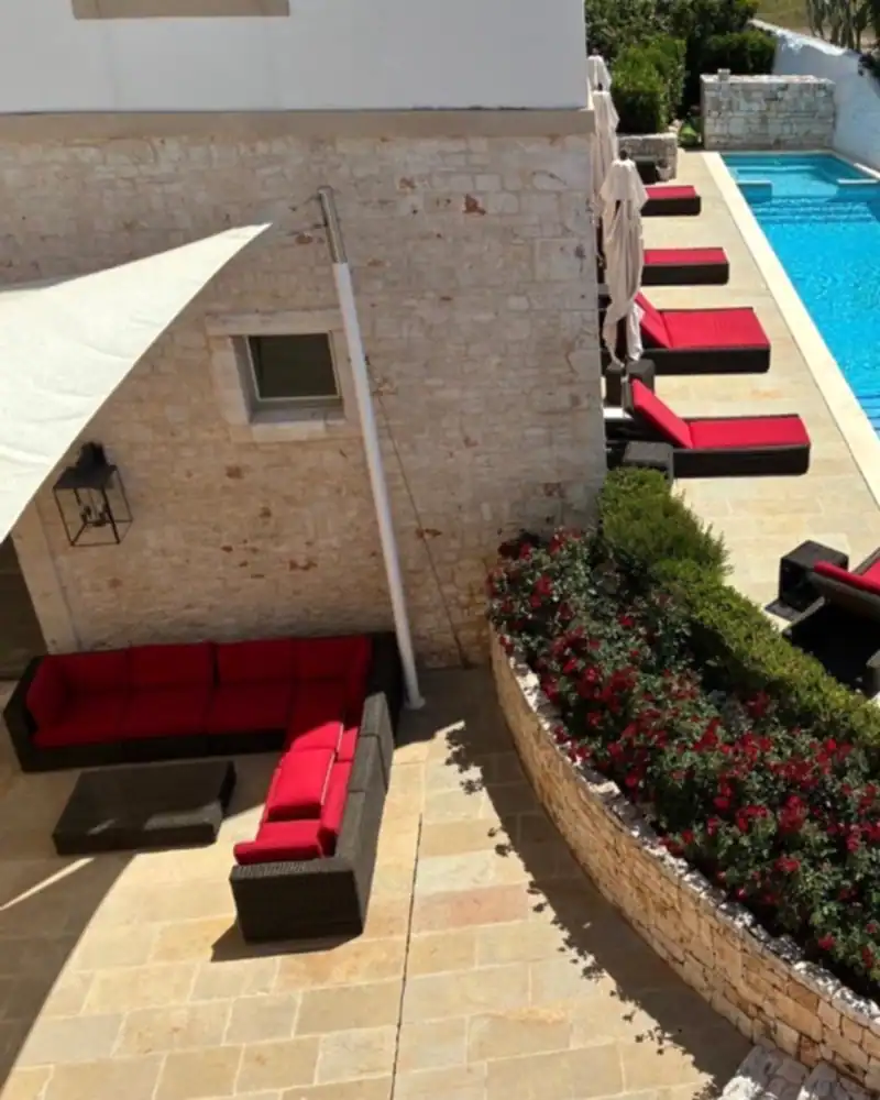 Piscina di una villa in pietra con aiuole fiorite