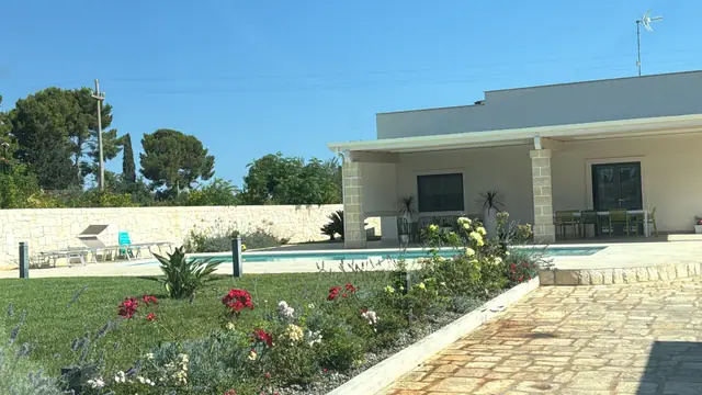 Villa con prato, rose e aiuole mediterranee accanto alla piscina